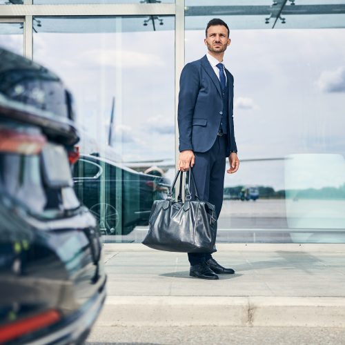 Elegant businessman waiting for a shuttle bus near the airport